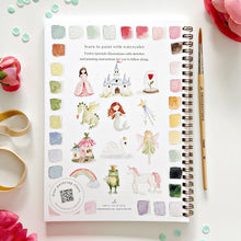 Load image into Gallery viewer, Watercolor art book with illustrations of fairies, castles, and other fantasy elements on a white surface with flowers and a pen.