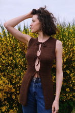 Load image into Gallery viewer, Woman wearing a brown sleeveless knitted top with a yellow flowering bush in the background