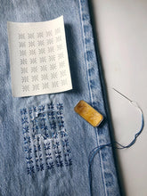 Load image into Gallery viewer, Denim fabric with a patterned template and embroidery tool on a white background