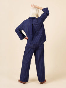 Person wearing a navy pinstripe pajama set on a beige background