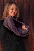 Load image into Gallery viewer, Woman holding a large purple knitted item against a wooden background