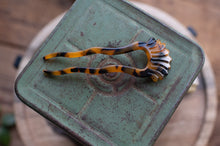 Load image into Gallery viewer, Decorative hair clip with tortoiseshell pattern on a textured green surface