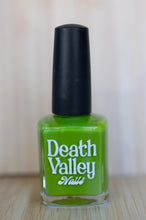 Load image into Gallery viewer, Green nail polish bottle with black cap on a wooden surface
