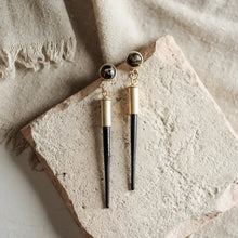 Load image into Gallery viewer, gold and black elements on a textured stone surface