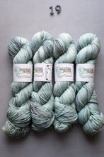 Load image into Gallery viewer, Four skeins of green yarn with labels on a gray background