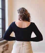 Load image into Gallery viewer, Person wearing a black long-sleeve top and beige pants, standing in a room with a window.