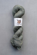 Load image into Gallery viewer, Skein of green yarn with a label on a gray background
