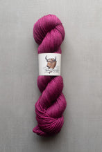 Load image into Gallery viewer, Pink skein of yarn with a label on a gray background