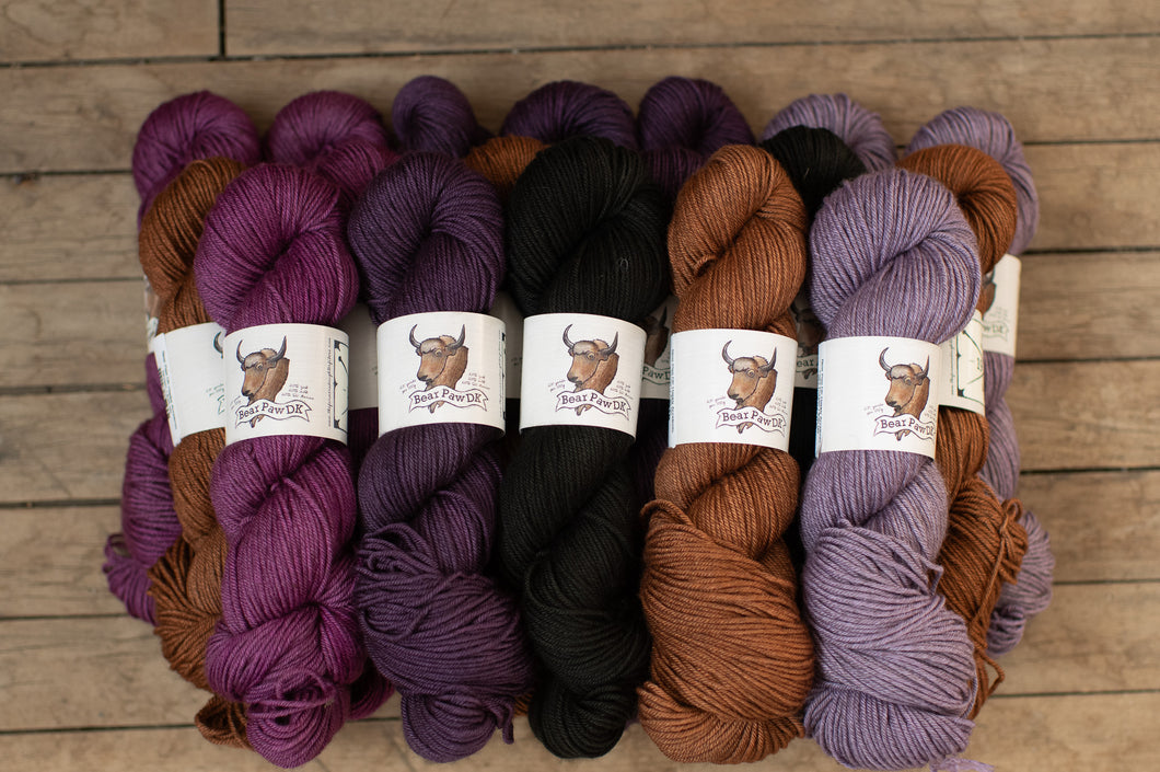 Bundles of yarn in various colors with labels on a wooden surface