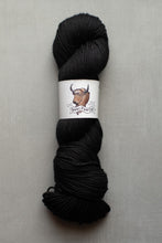 Load image into Gallery viewer, Black skein of yarn with a label on a gray background