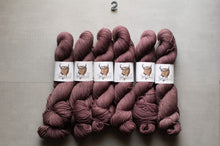 Load image into Gallery viewer, Six skeins of yarn in a dusty mauve-brown shade, arranged in two rows on a light gray background. Each skein is wrapped with a white paper label featuring a brown bull illustration.