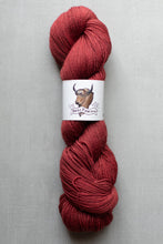Load image into Gallery viewer, A single skein of chunky yarn in a deep rust red color, wrapped with a white paper label featuring a bison illustration