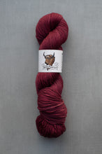 Load image into Gallery viewer, Red skein of yarn with a label on a gray background
