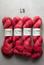 Load image into Gallery viewer, Four skeins of red yarn with labels on a gray background