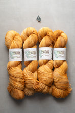 Load image into Gallery viewer, Four skeins of orange yarn with labels on a gray background