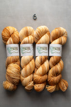Load image into Gallery viewer, Four skeins of light brown yarn with labels on a gray background