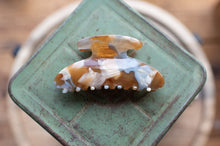 Load image into Gallery viewer, Decorative hair clip on a green stand with a blurred background