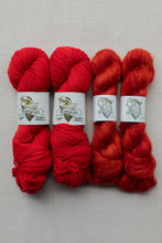 Load image into Gallery viewer, Four skeins of yarn in shades of red arranged side by side on a light gray textured background. Each skein has a white paper label wrapped around it with the brand name 'Piskum' and a ram illustration.