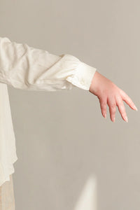 White long-sleeve garment with a blurred background