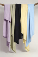 Five colorful scarves hanging on a wooden rod against a neutral background