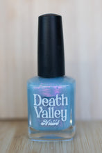 Load image into Gallery viewer, Blue nail polish bottle with black cap on a light wooden surface