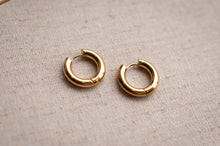 Load image into Gallery viewer, Pair of gold hoop earrings on a beige fabric background