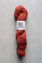 Load image into Gallery viewer, Red skein of yarn with a label on a gray background
