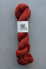 Load image into Gallery viewer, Red skein of yarn with a label on a gray background