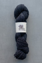 Load image into Gallery viewer, Dark gray skein of yarn with a label on a gray background