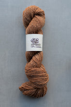 Load image into Gallery viewer, Brown skein of yarn with a label on a gray background