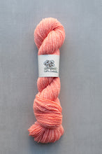 Load image into Gallery viewer, Peach-colored yarn skein with a label on a gray background