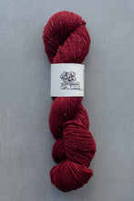 Load image into Gallery viewer, Red skein of yarn with a label on a gray background