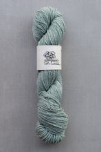 Load image into Gallery viewer, Skein of teal yarn with a label on a gray background