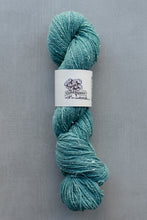Load image into Gallery viewer, Teal skein of yarn with a label on a gray background