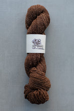 Load image into Gallery viewer, Brown skein of yarn with a label on a gray background