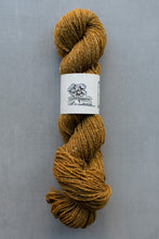 Load image into Gallery viewer, Mustard yellow skein of yarn with a label on a gray background