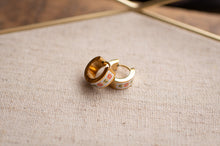 Load image into Gallery viewer, Gold hoop earrings with floral design on a textured fabric surface