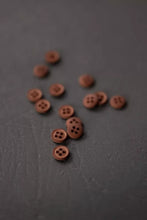 Load image into Gallery viewer, Small brown buttons scattered on a dark surface