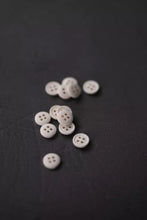 Load image into Gallery viewer, White buttons scattered on a dark surface