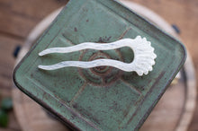 Load image into Gallery viewer, White hairpin on a textured green surface