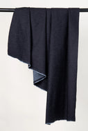 Dark gray fabric draped over a black rod on a light gray background