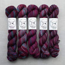 Load image into Gallery viewer, Five skeins of maroon and blue yarn with Spincycle Yarns labels on a gray background