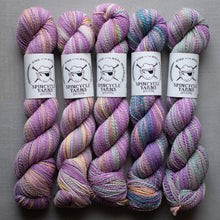 Load image into Gallery viewer, Five skeins of purple and pink yarn with visible brand labels on a gray background