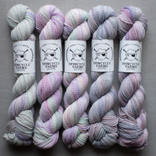 Load image into Gallery viewer, Five skeins of multicolored yarn with Spincycle Yarns labels on a gray background