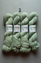 Load image into Gallery viewer, Four skeins of sage green yarn with white paper bands labeled 'Great Falls Mountain' arranged side by side on a gray background, with a small black number 2 above them.