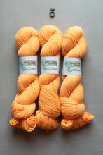 Load image into Gallery viewer, Three skeins of bright orange yarn with white paper bands labeled 'Great Falls Montana' are arranged vertically on a neutral gray background, with a small black number 5 centered above them.