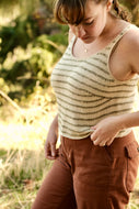 Woman wearing a striped tank top and brown pants in a natural setting
