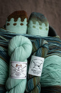 Two skeins of yarn with labels on a textured surface