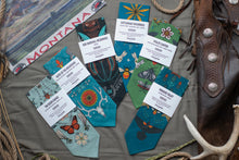Load image into Gallery viewer, Collection of Montana-themed greeting cards and stationery items on a textured surface with a leather bag and antlers.