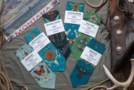 Collection of Montana-themed greeting cards and stationery items on a textured surface with a leather bag and antlers.